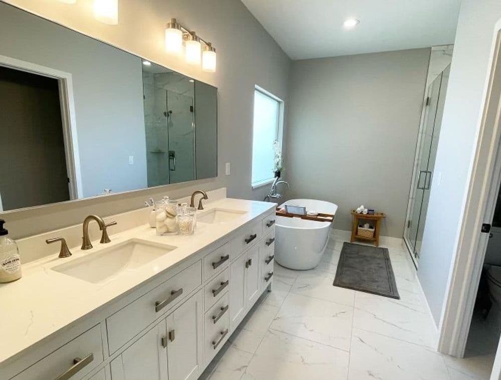 Modern bathroom with double sinks, freestanding tub, and sleek gray walls and floors.
