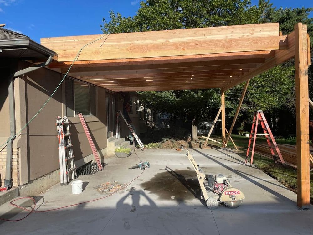 Wooden deck construction in progress with scaffolding, tools, and a clear blue sky.
